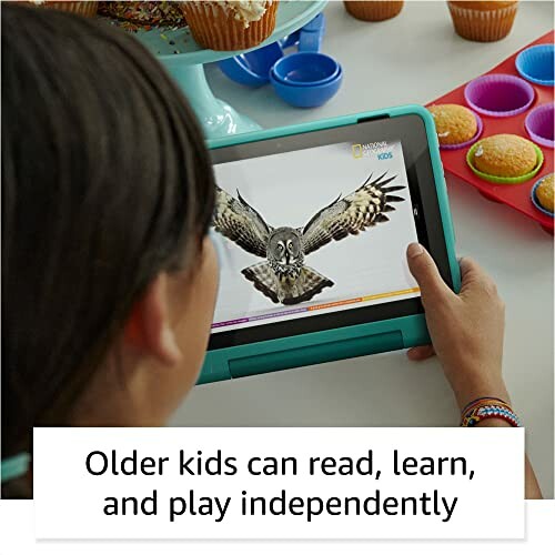 Child using a tablet with an educational app, surrounded by cupcakes.