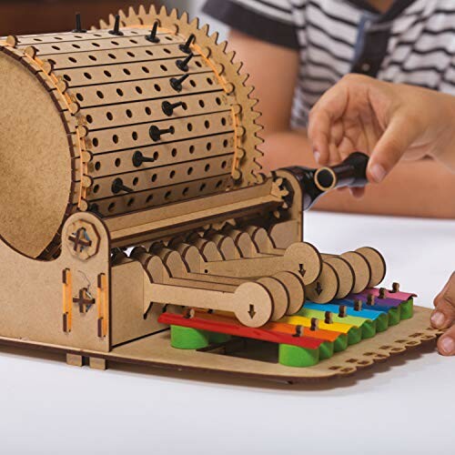 Hands interacting with a wooden mechanical music box model.